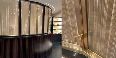 Curved wall made of polished wood and brass with panes of glass inside a heath spa reception area